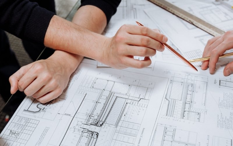 multiple people marking up blueprints